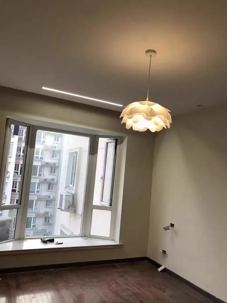 מנורת תלייה בעיצוב מינימליסטי בחדר עם חלון גדול ורצפת עץ כהה