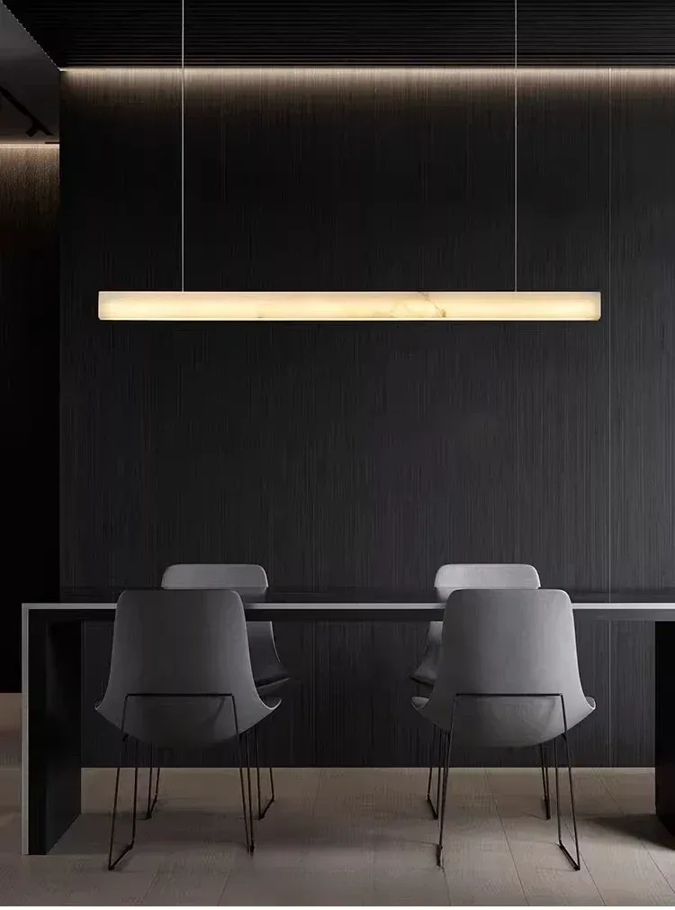 מנורת תלייה מלבנית מעל שולחן כהה וכיסאות אפורים