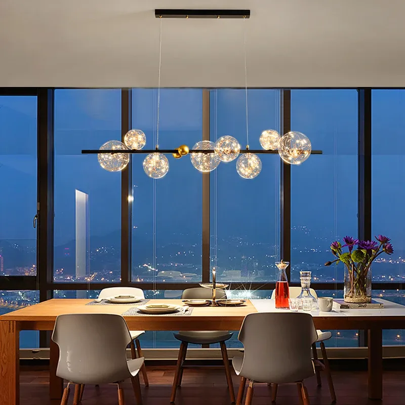 נברשת מודרנית עם כדורים שקופים מעל שולחן אוכל ליד חלון גדול