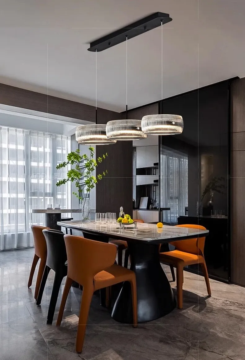 נברשת מודרנית מעל שולחן אוכל עם כיסאות כתומים