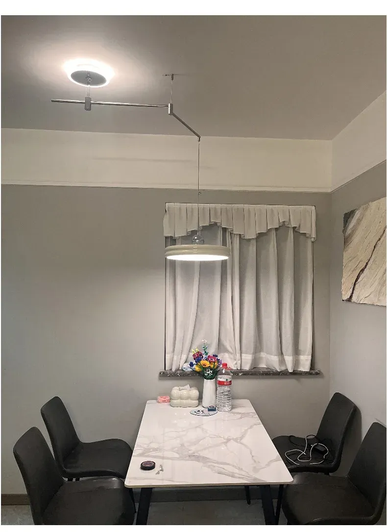 מנורה עגולה תלויה מעל שולחן שיש עם כיסאות שחורים