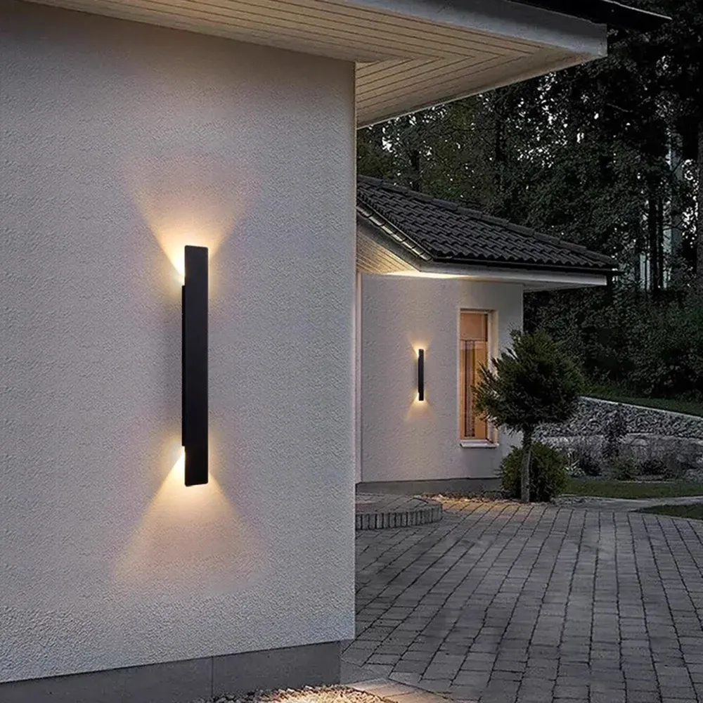 מנורת קיר שחורה על קיר חיצוני עם שביל מרוצף