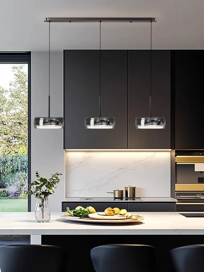 תאורה תלויה מעל אי במטבח כהה עם עיצוב מודרני