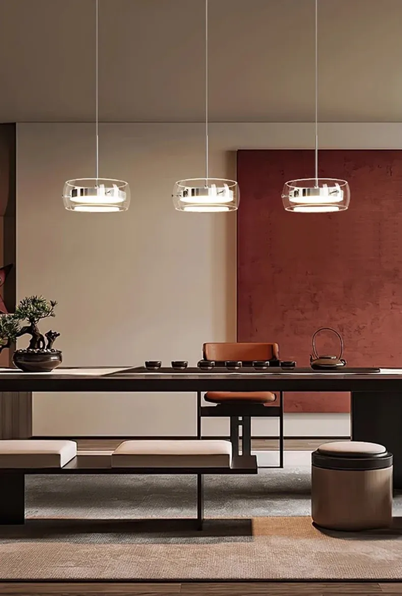 שלושה גופי תאורה תלויים בחדר אוכל עם קיר אדום