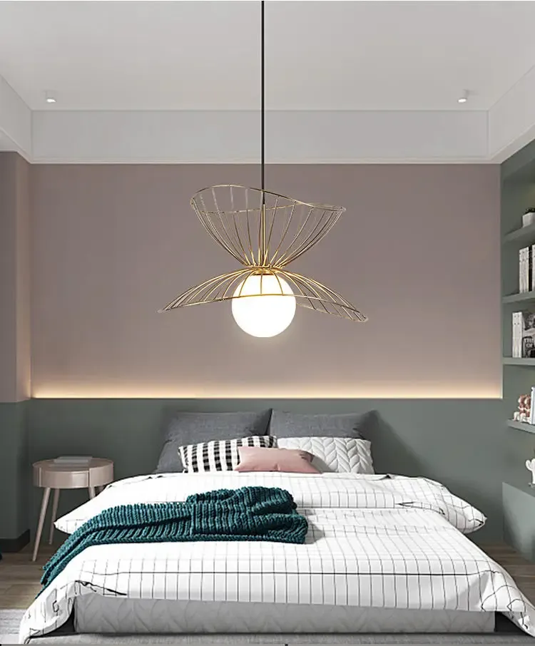 מנורת תלייה זהובה בחדר שינה עם מיטה מסודרת