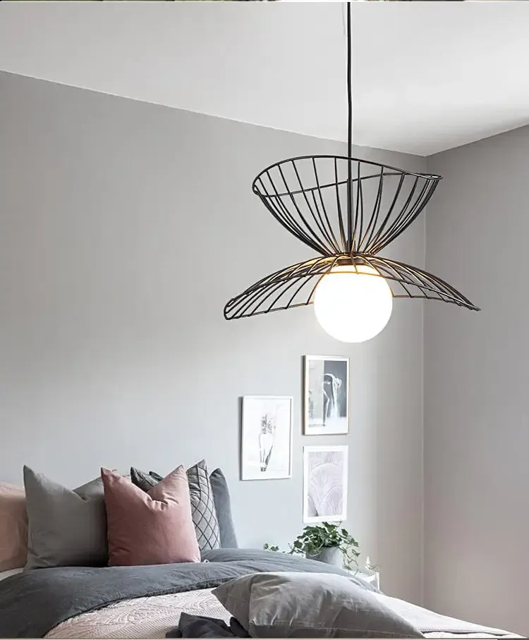 מנורת תלייה שחורה בחדר שינה עם כריות ורודות