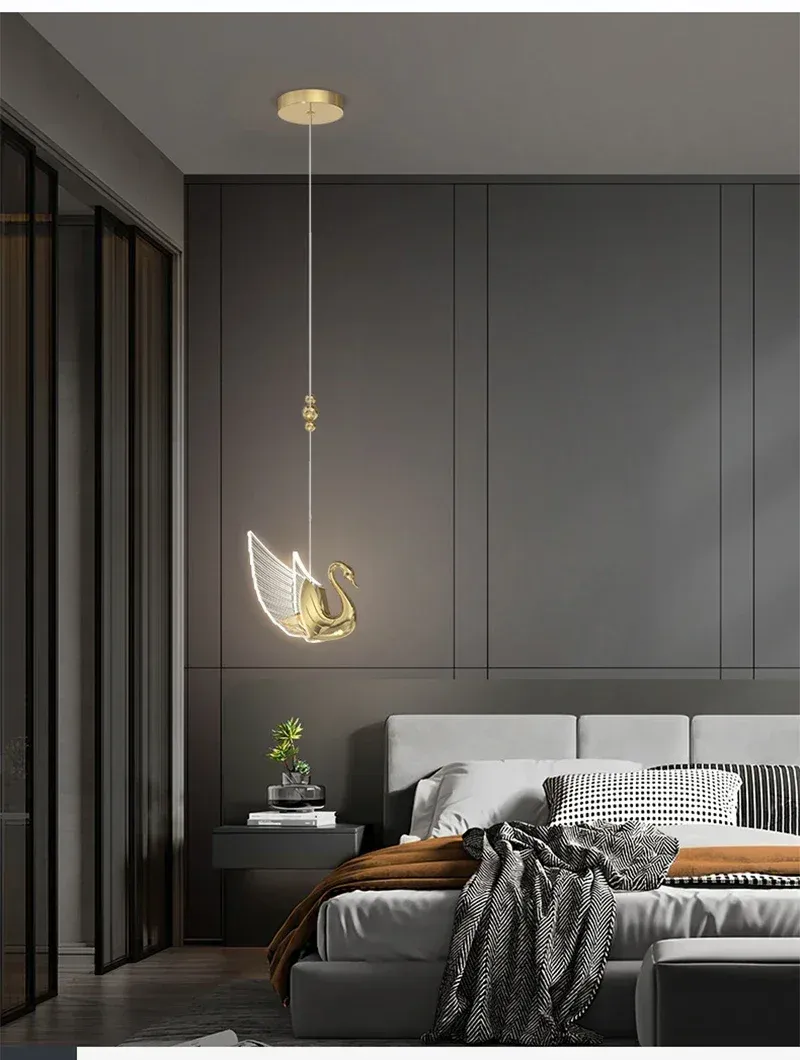 שני ברבורים מוזהבים כתאורה מעל מיטה אפורה