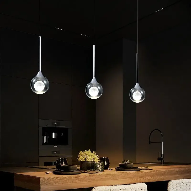 שלוש מנורות תלויות מעל שולחן אוכל בחדר חשוך