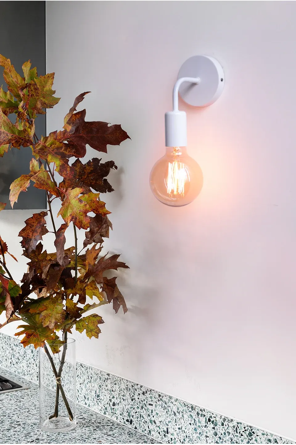 מנורת קיר לבנה ליד עלים יבשים במטבח