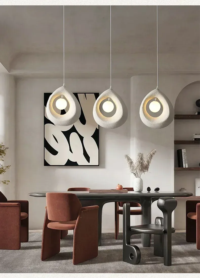 שלוש מנורות תלייה מעל שולחן אוכל בחדר מודרני