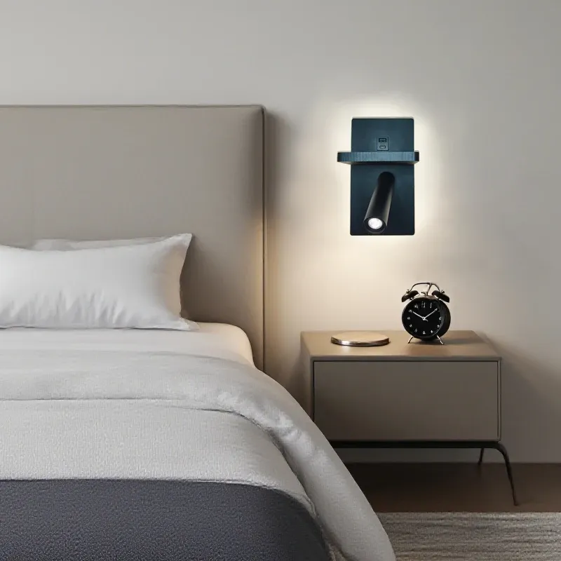 מנורת קיר שחורה ליד מיטה עם כרית לבנה