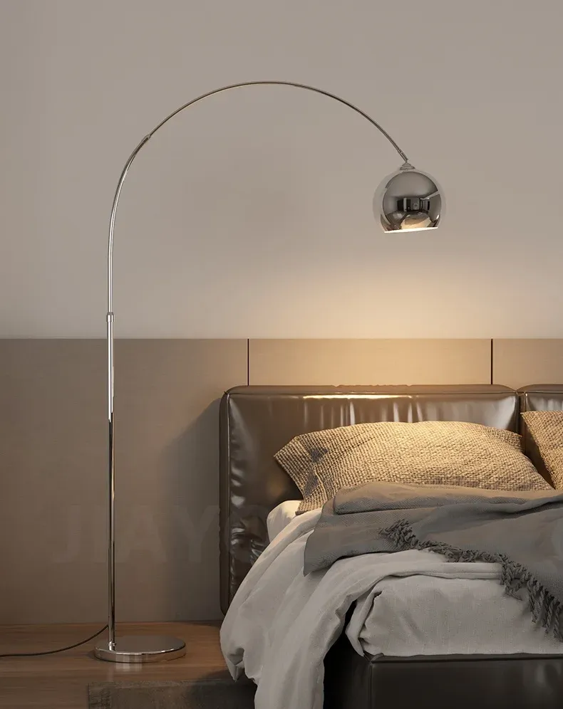 מנורה כסופה ליד מיטה עם מצעים אפורים