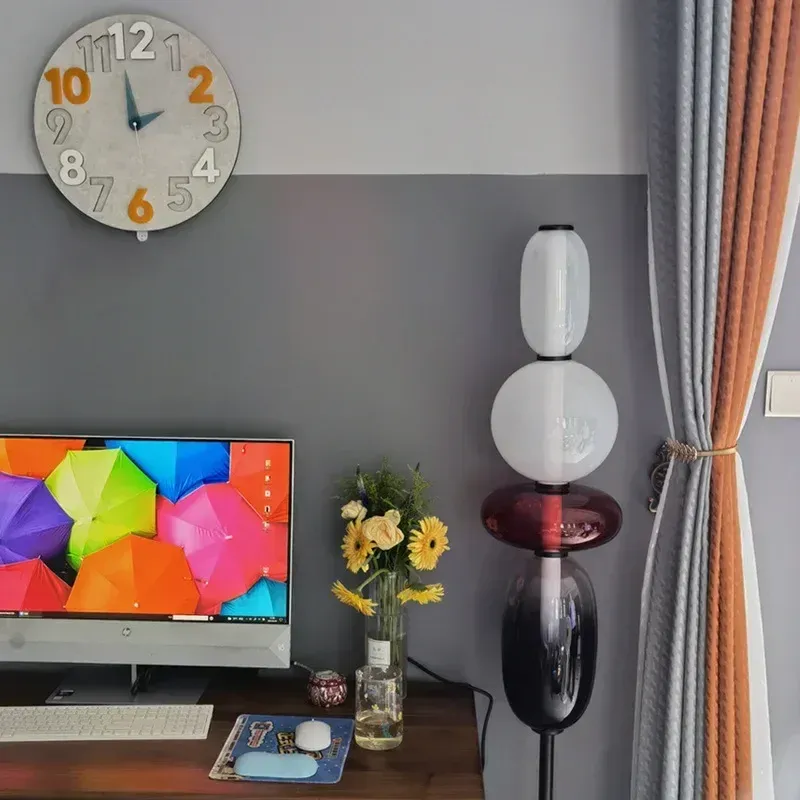 מנורת זכוכית ליד מחשב עם רקע צבעוני וקיר אפור