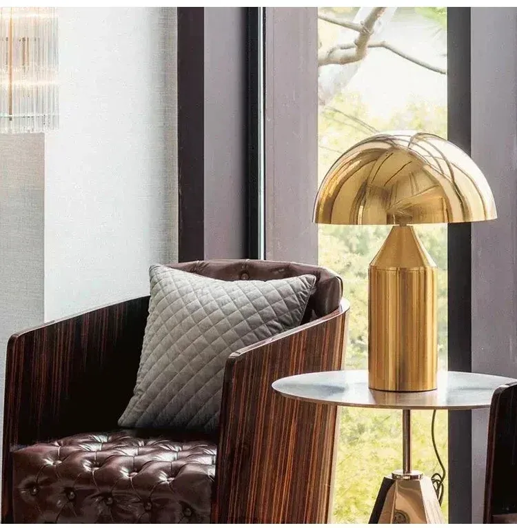 מנורת שולחן זהב ליד כורסה עם כרית אפורה