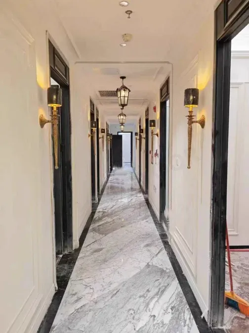 מסדרון עם מנורות קיר נחושת ואהילים שחורים